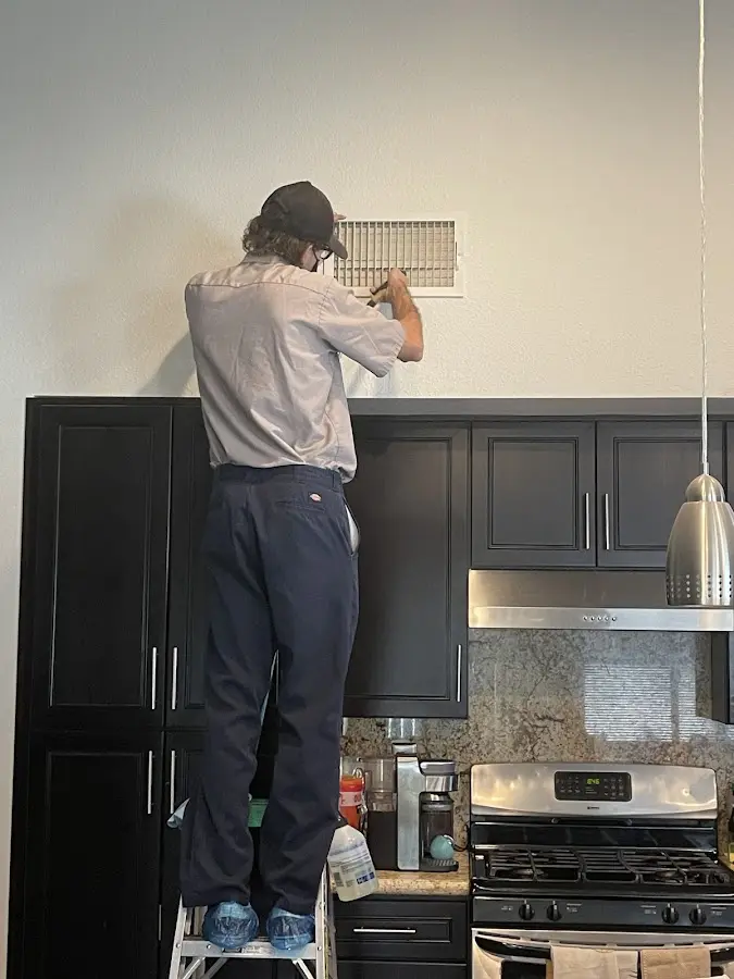 Technician inspecting an air vent during HVAC service in Wake Forest